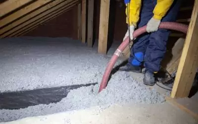 a man installing blown in insulation into an attic